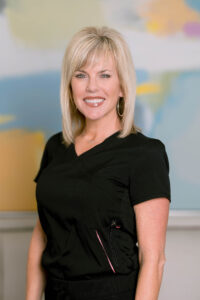 Friendly woman with blonde hair, showcasing confident smile, at Dr. Behmand’s practice.